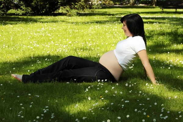 Piękna ciężarna kobieta relaksująca się w parku — Zdjęcie stockowe