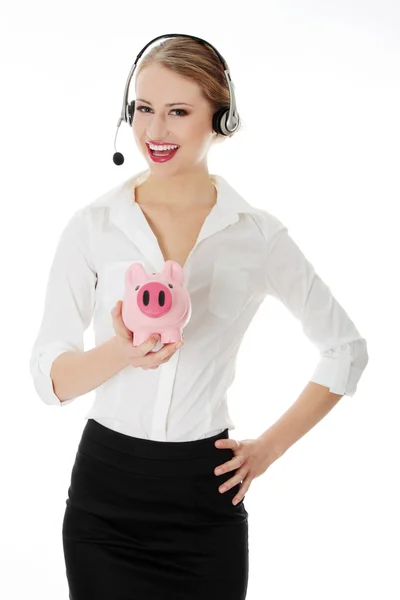 Młoda kobieta z zestawu słuchawkowego piggy bank gospodarstwa — Zdjęcie stockowe