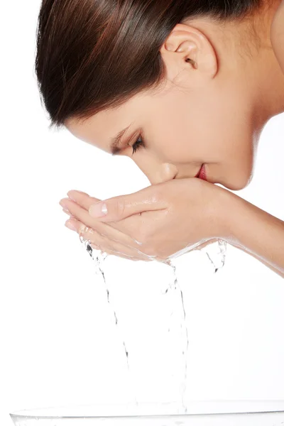 Mujer joven lavándose la cara con agua clara — Foto de Stock