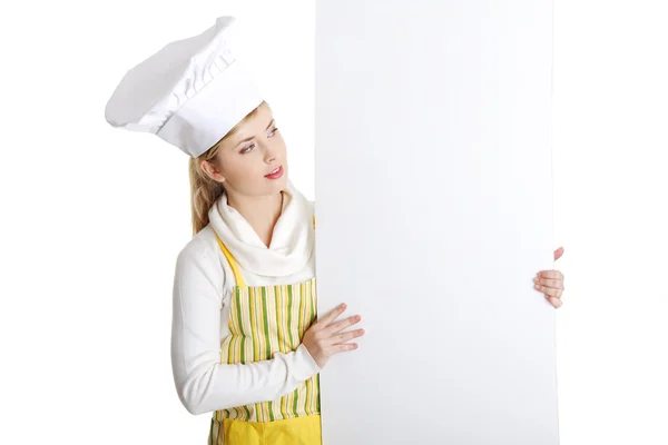 Mulher feliz cozinheiro ou padeiro olhando sobre cartaz sinal de papel . — Fotografia de Stock