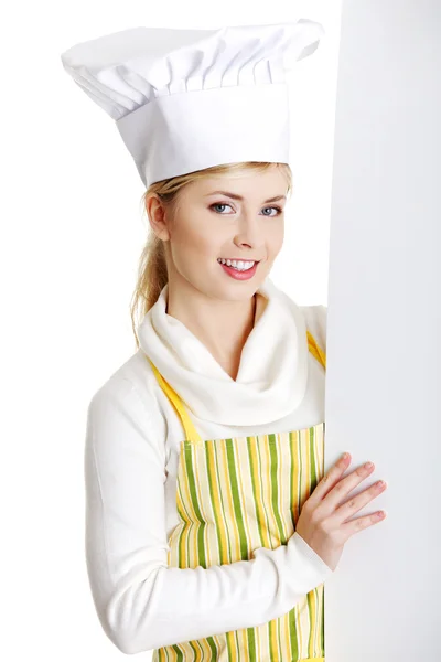 Счастливая женщина повар или пекарь, глядя на бумажный рекламный щит . — стоковое фото