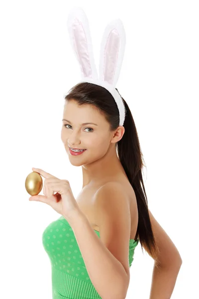Mladá dívka s Velikonoční zajíček uši drží zlaté vejce — Stock fotografie