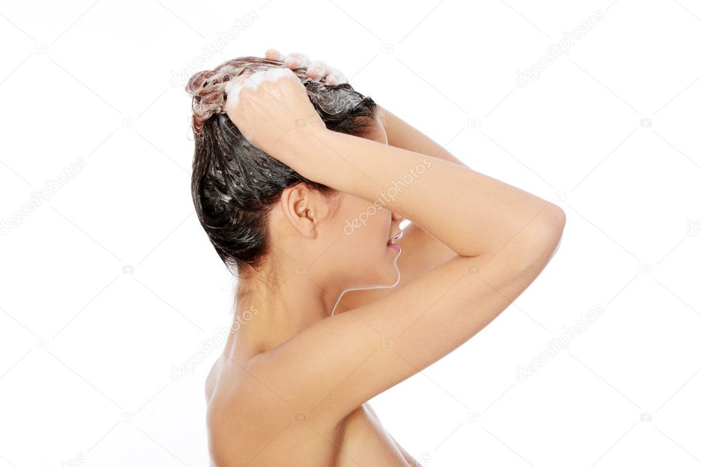 Beautiful young woman washing her hair with shampoo