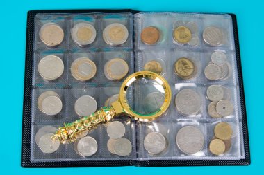 Magnifying glass and album with a collection of coins clipart