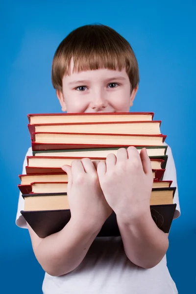 Мальчик с грудой книг — стоковое фото