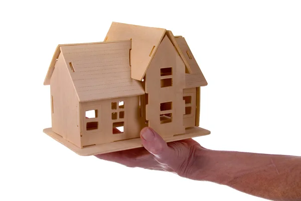 Ręka trzymająca drewniany dom — Zdjęcie stockowe