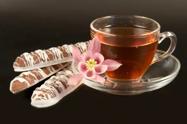 Bílý šálek s čajem, soubory cookie a květiny — Stock fotografie