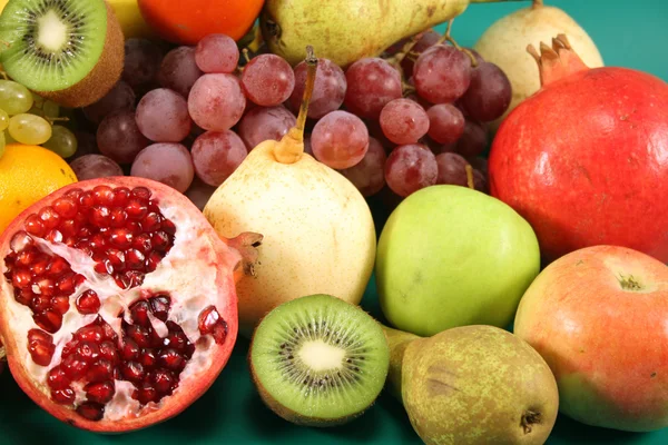 Verschiedene Früchte auf grünem Hintergrund. — Stockfoto