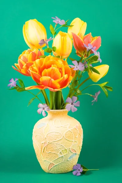 Vase with bouquet of tulips on a green background. — Stock Photo, Image