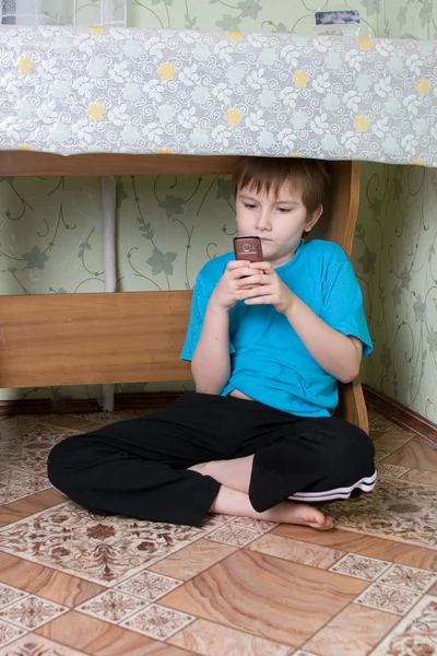 Boy sits under a table — Stock Photo, Image