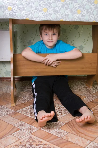 男孩坐在一张桌子底下 — 图库照片