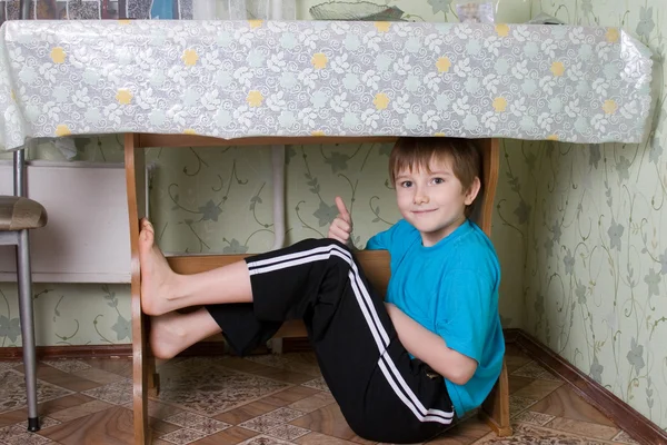 Αγόρι κάθεται κάτω από το τραπέζι — Φωτογραφία Αρχείου