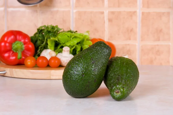 Avocado against fresh vegetables — Stock Photo, Image