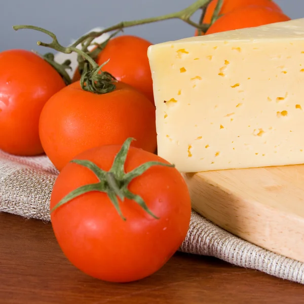 Queijo amarelo com tomates frescos — Fotografia de Stock