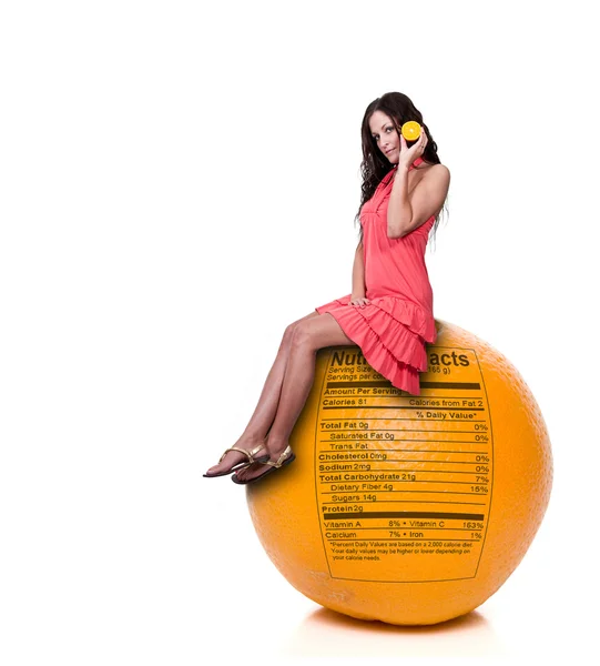 Mujer sentada en naranja con etiqueta nutricional — Foto de Stock