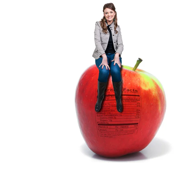 Mujer sentada en la manzana roja deliciosa con etiqueta nutricional —  Fotos de Stock