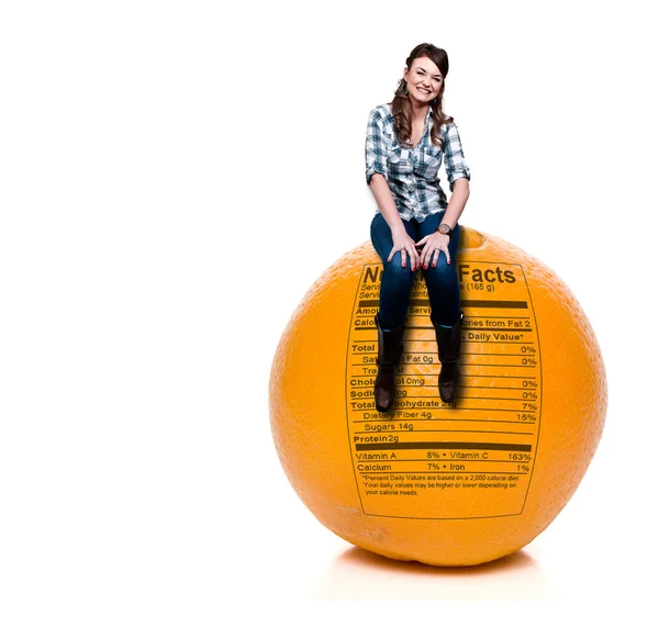 Kvinna sitter på orange med näringsvärdesdeklarationen — Stockfoto