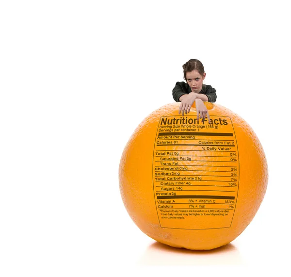 Adolescente donna in piedi dietro arancione con etichetta nutrizionale — Foto Stock