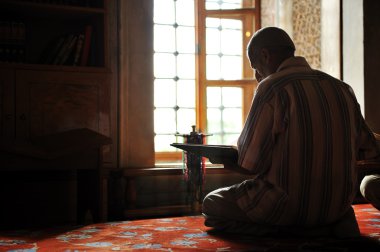 Muslim reading Koran inside mosque clipart