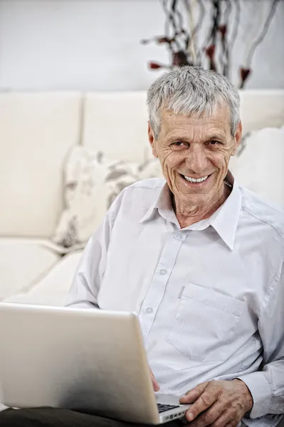 高级男子在家里的沙发上使用笔记本电脑轻松 — 图库照片