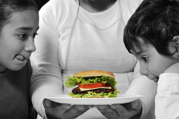 Madre dando una hamburguesa a hijo e hija — Foto de Stock