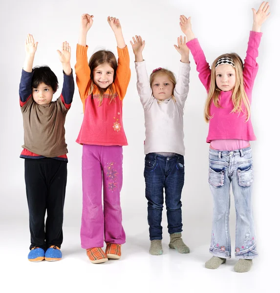 Skupina čtyř dětí s rukama nahoru — Stock fotografie