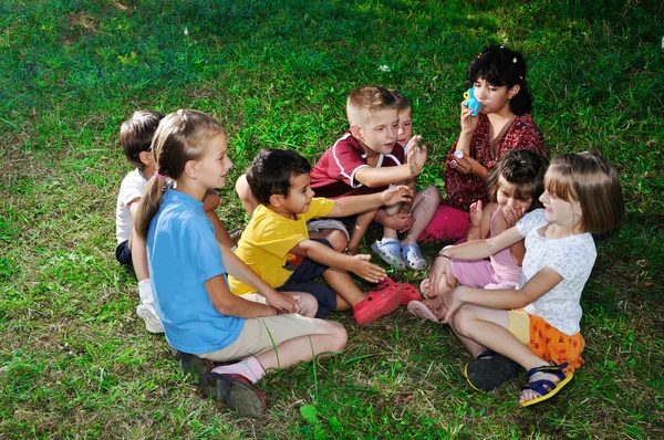 Foto de crianças felizes brincando e soprando bolhas de sabão — Fotografia de Stock