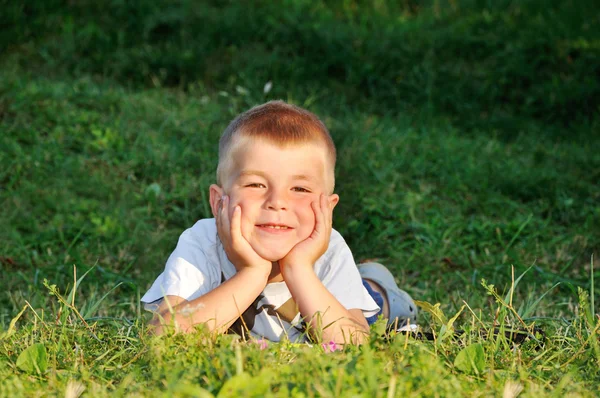 실제로 카메라를 보고 잔디에 누워 행복 한 소년 — 스톡 사진