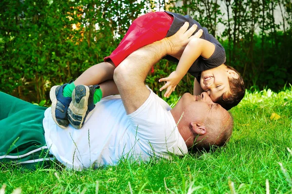Un padre y su hijo tendidos y sonriendo en la hierba — Foto de Stock