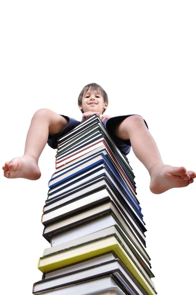 Menino sentado em grande pilha de livros — Fotografia de Stock