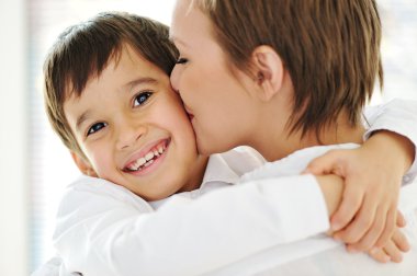 Happy mother embracing and kissing her son clipart