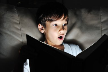 Shocked kid reading book, light in darkness clipart