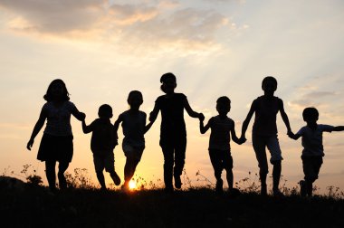 Children running on meadow at sunset time clipart