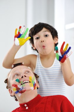 Kid and his mother playing with messy colors clipart