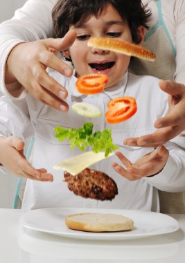 Mother and son making burger at kitchen clipart