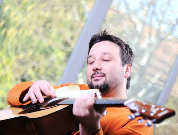 Gitar çalmak ve evde rahatlatıcı bir adam — Stok fotoğraf