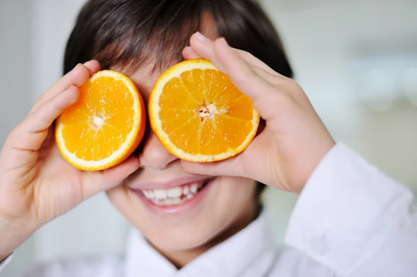 Pequeño niño jugando con frutas frescas de naranja — Foto de Stock