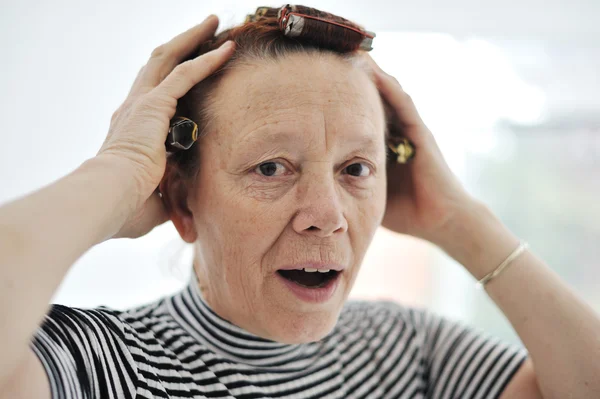 Senior dame met krulspelden op haar — Stockfoto