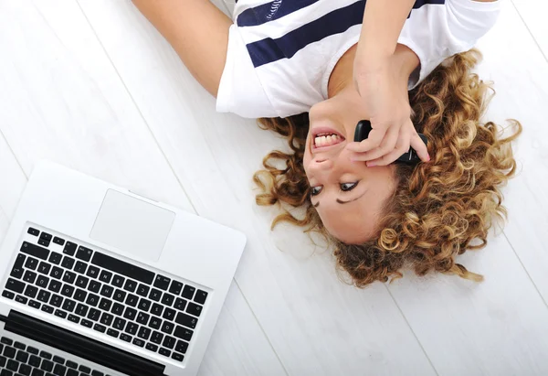 Härlig tjej med laptop och telefon hemma — Stockfoto