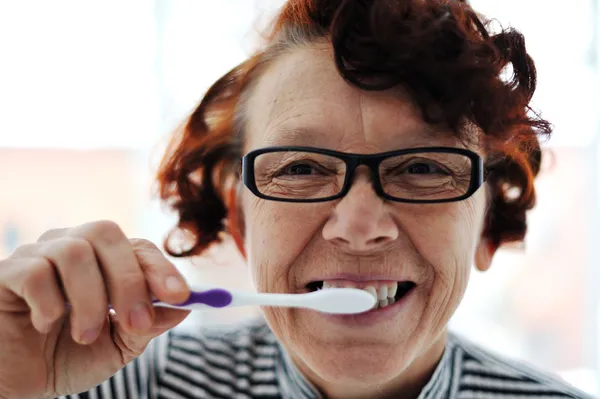 Mujer mayor cepillándose los dientes — Foto de Stock