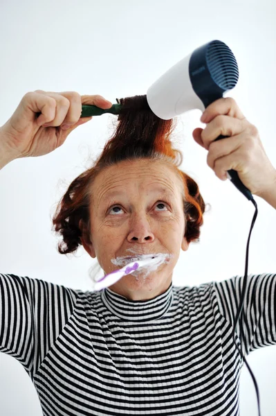 Diş fırçalama ve saç kurutma kadın kıdemli — Stok fotoğraf
