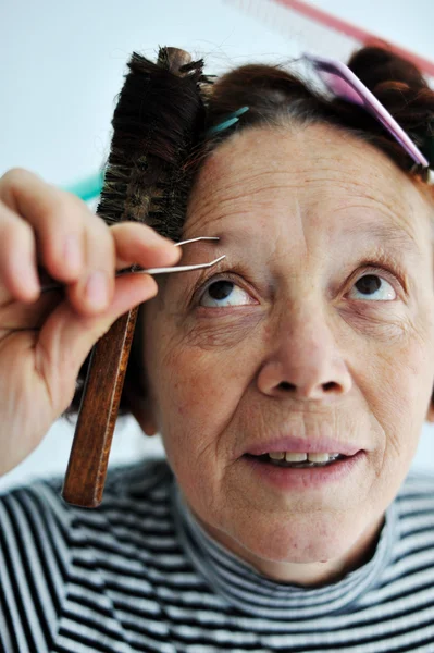 Старша жінка, що пінцює брови — стокове фото
