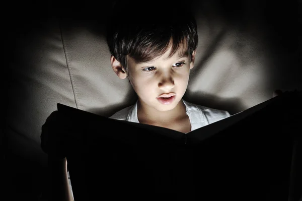 Kid reading book, light in darkness — Stock Photo, Image