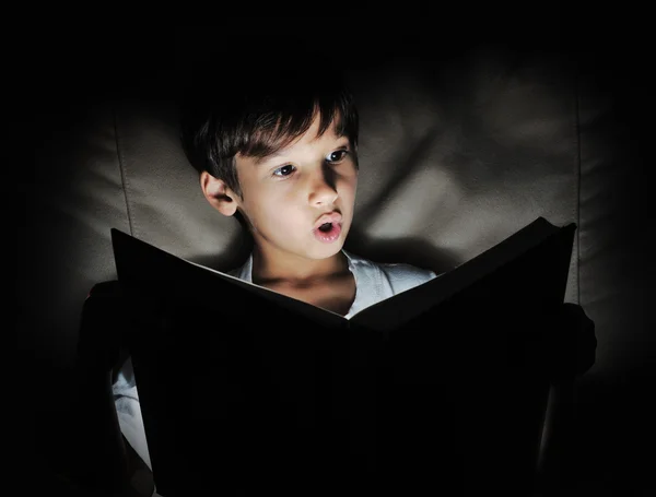 Kid läsa bok, ljus i mörker — Stockfoto