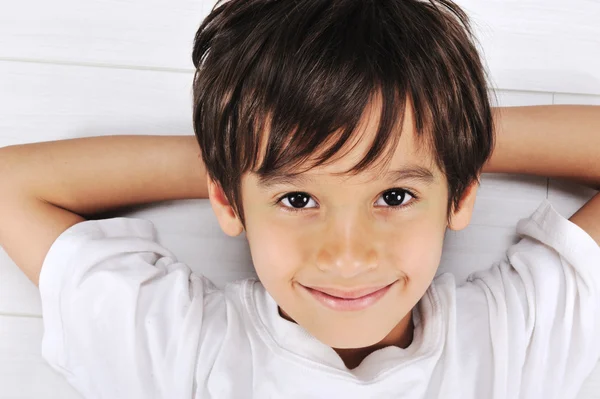 Μικρό αγόρι περί χαλαρή σε λευκό δάπεδο στο σπίτι — Φωτογραφία Αρχείου