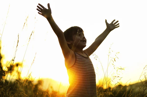 Šťastné dítě těší v přírodě při západu slunce — Stock fotografie