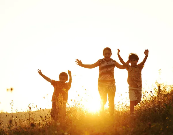 Crianças correndo no prado ao pôr do sol — Fotografia de Stock
