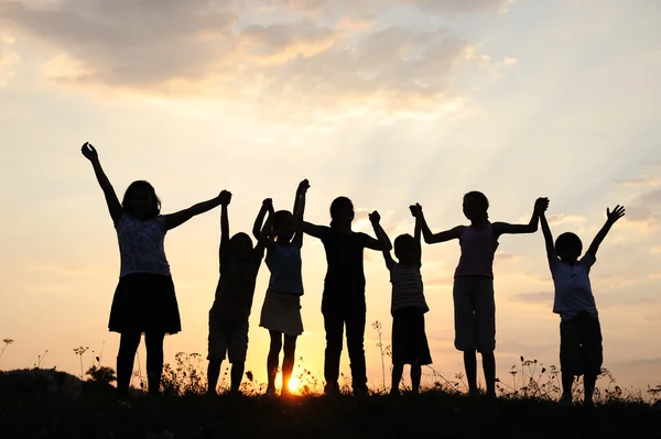 Grupo de crianças felizes brincando no pôr do sol de verão — Fotografia de Stock