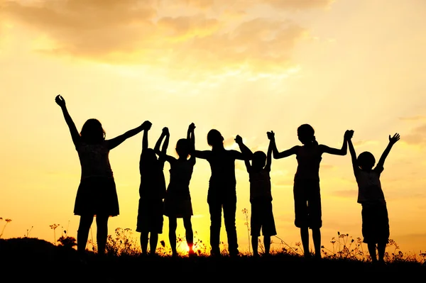 Skupina šťastných dětí, které hrají při západu slunce v létě v přírodě — Stock fotografie
