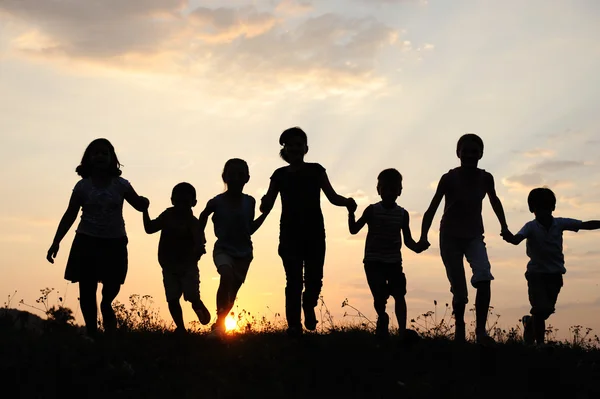 Děti běží na louce v době západu slunce — Stock fotografie